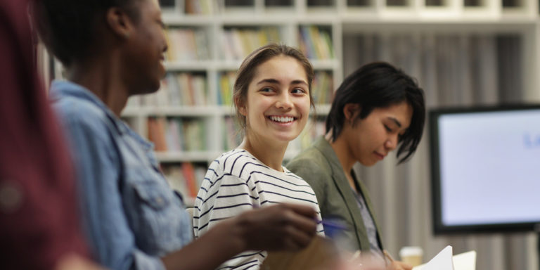 Teenagers sitting in a library working together.